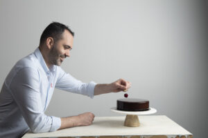 Chef Dominique placing a cherry on top of a cake